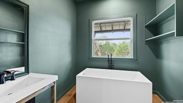 laundry room featuring baseboards, a sink, and wood finished floors