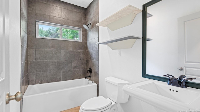 bathroom with a sink, tub / shower combination, and toilet