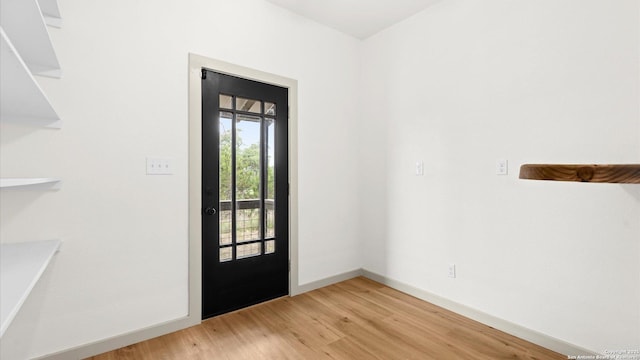doorway with baseboards and light wood finished floors