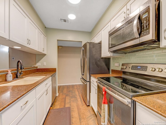 kitchen featuring a sink, appliances with stainless steel finishes, white cabinets, and visible vents