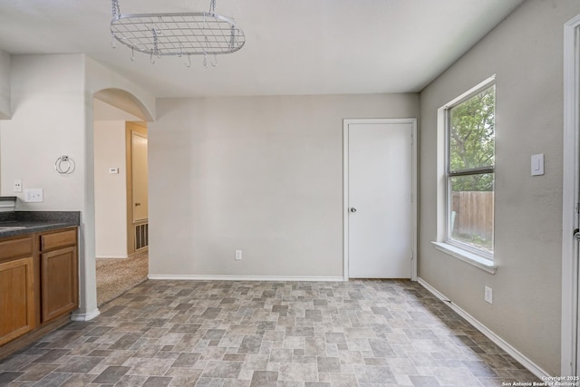 unfurnished room with stone finish floor, baseboards, arched walkways, and visible vents