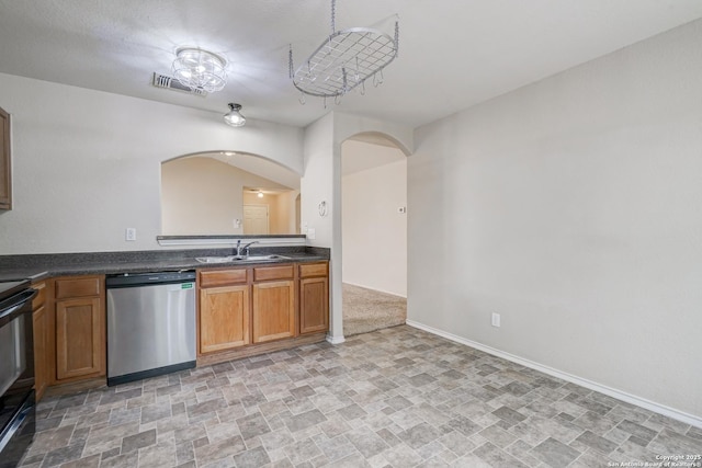 kitchen with visible vents, a sink, arched walkways, stone finish flooring, and dishwasher