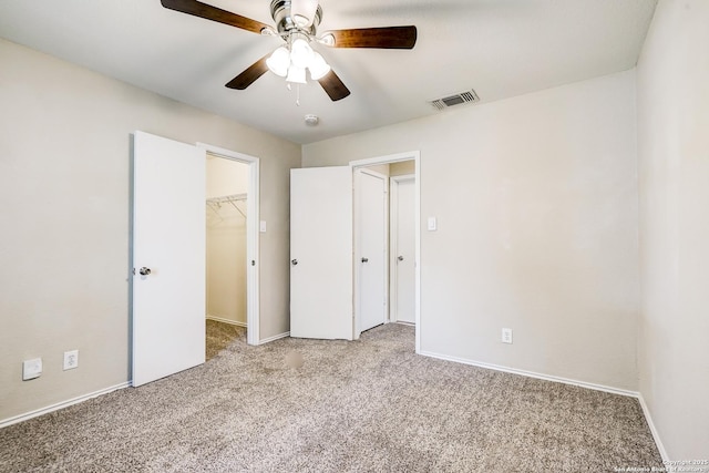 unfurnished bedroom featuring visible vents, carpet, a walk in closet, and baseboards