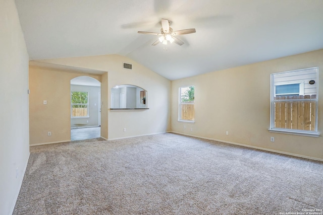 carpeted empty room featuring a ceiling fan, visible vents, arched walkways, vaulted ceiling, and baseboards