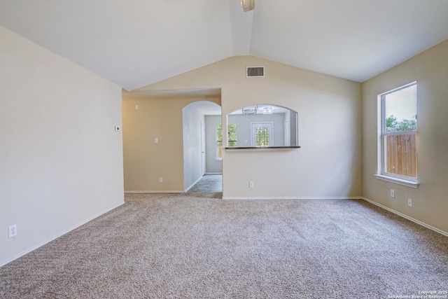 spare room featuring visible vents, arched walkways, carpet, and lofted ceiling