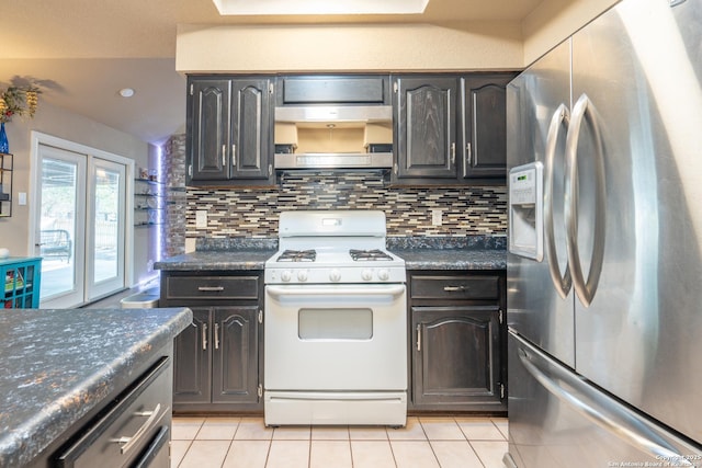 kitchen featuring light tile patterned flooring, dark countertops, white range with gas stovetop, backsplash, and stainless steel refrigerator with ice dispenser