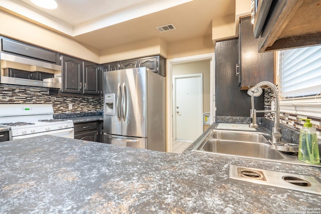 kitchen with dark countertops, appliances with stainless steel finishes, a sink, tasteful backsplash, and visible vents