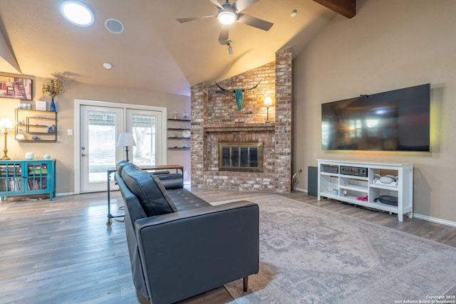 living area with beam ceiling, wood finished floors, a fireplace, baseboards, and ceiling fan
