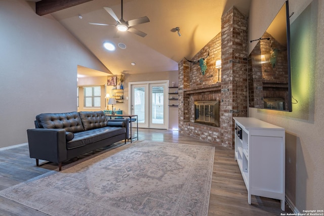 living room with a ceiling fan, a brick fireplace, wood finished floors, high vaulted ceiling, and beamed ceiling