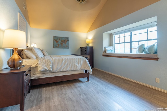 bedroom with baseboards, visible vents, wood finished floors, and lofted ceiling