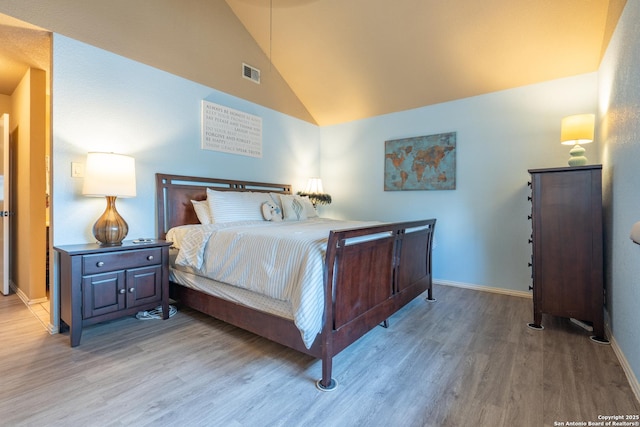 bedroom featuring baseboards, visible vents, wood finished floors, and high vaulted ceiling