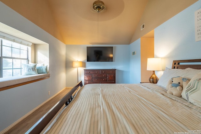 bedroom featuring baseboards, vaulted ceiling, wood finished floors, and visible vents