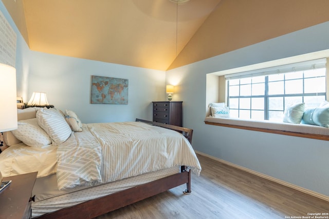 bedroom featuring baseboards, wood finished floors, and high vaulted ceiling
