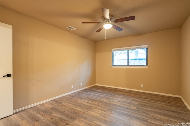 spare room with visible vents, a ceiling fan, baseboards, and wood finished floors