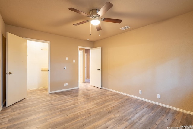 unfurnished bedroom featuring baseboards, a walk in closet, light wood-type flooring, and visible vents