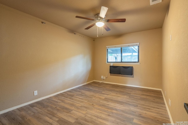 unfurnished room with a ceiling fan, baseboards, visible vents, and wood finished floors