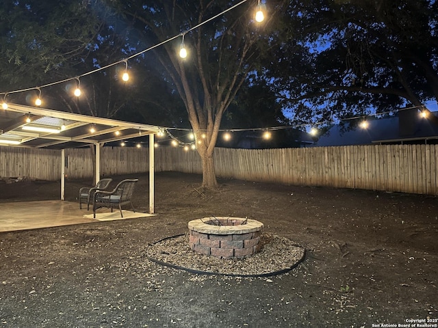yard at twilight with a fenced backyard, a fire pit, and a patio area