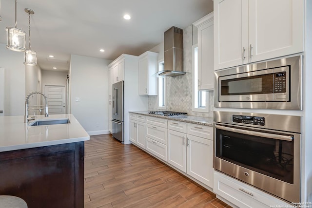8314 Marek, San Antonio, TX 78224 - kitchen with appliances with stainless steel finishes, light wood-type flooring, a sink, light countertops, and wall chimney exhaust hood