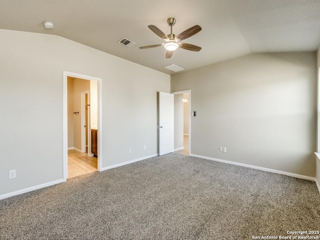 unfurnished bedroom with baseboards, vaulted ceiling, light carpet, and visible vents