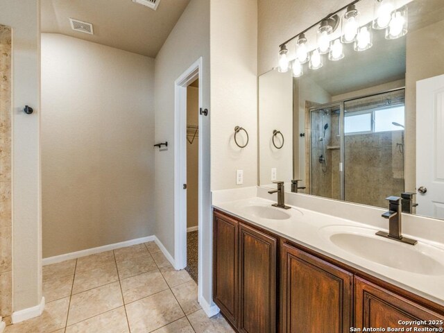 full bathroom with double vanity, a walk in closet, a sink, and a stall shower