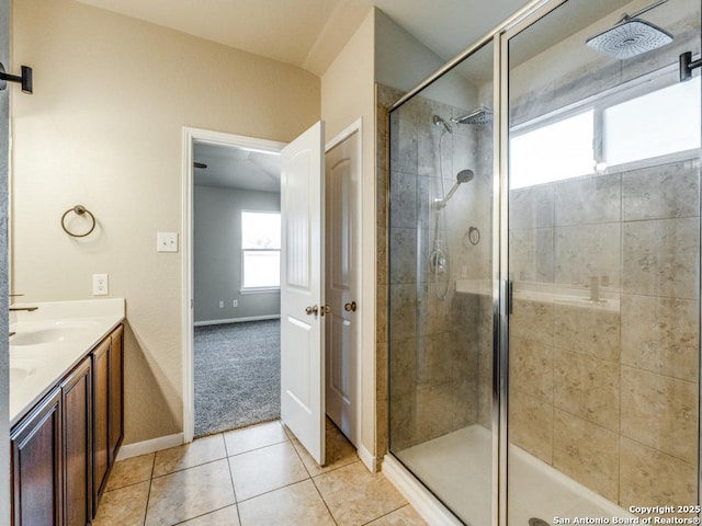 bathroom with a sink, tile patterned floors, baseboards, and a stall shower