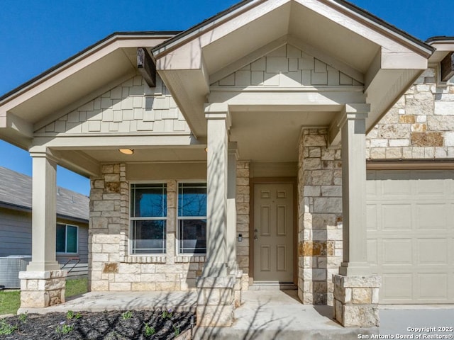 view of exterior entry featuring covered porch, central AC, stone siding, and a garage