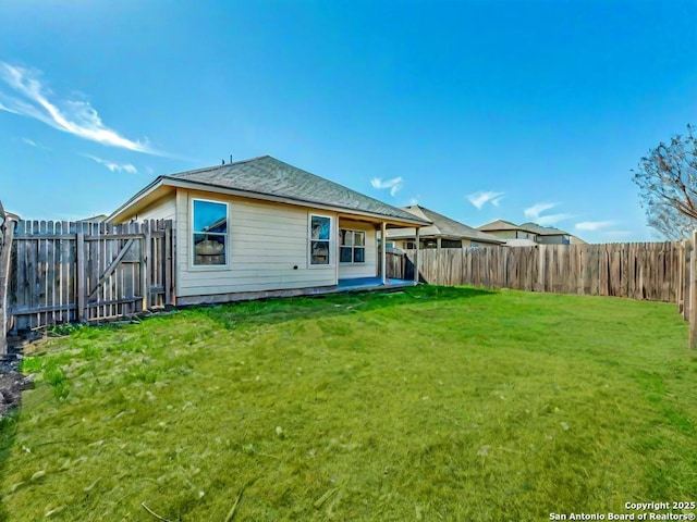 back of property with a fenced backyard and a yard