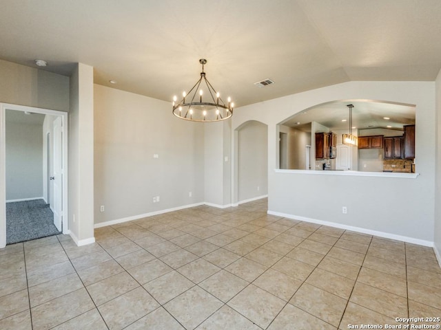 spare room with visible vents, arched walkways, light tile patterned flooring, and a chandelier