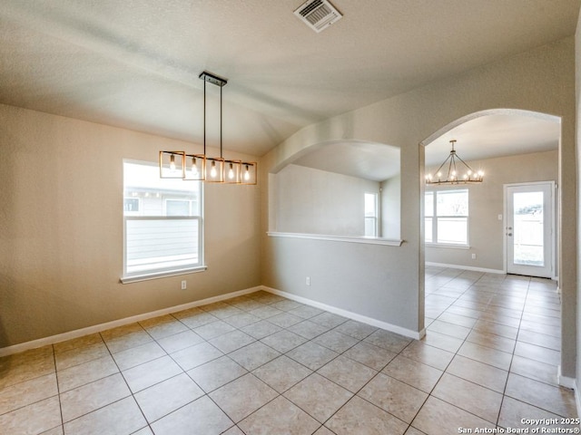 spare room featuring light tile patterned floors, arched walkways, baseboards, and visible vents