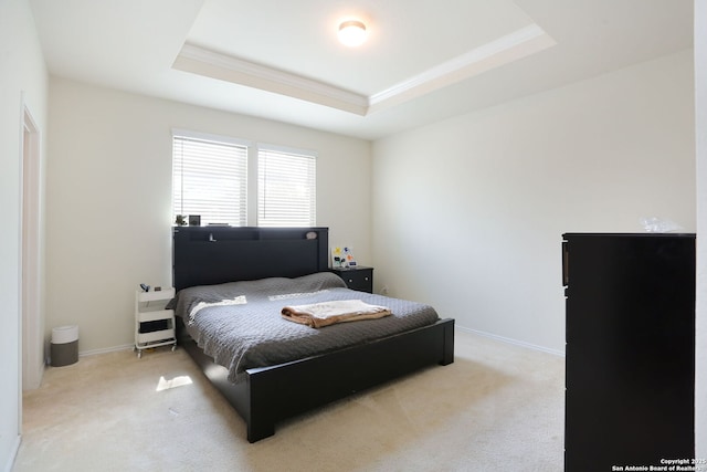 bedroom featuring crown molding, a tray ceiling, baseboards, and carpet