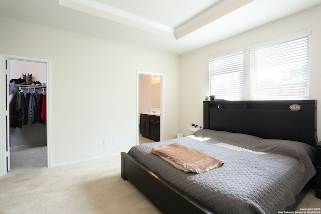 bedroom with crown molding, a closet, light carpet, a walk in closet, and a raised ceiling
