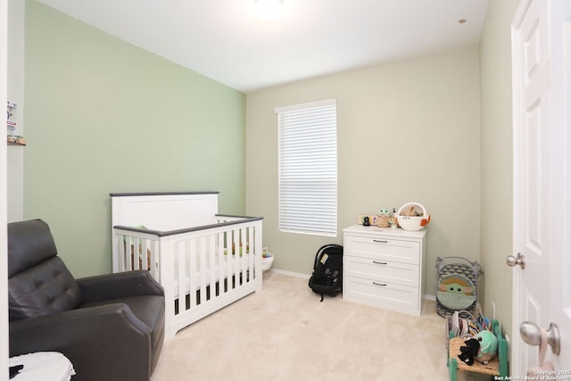 bedroom with baseboards, light colored carpet, and a crib