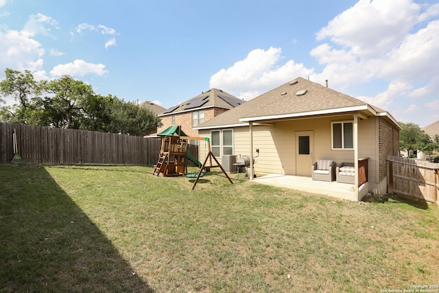 back of house featuring a patio, a fenced backyard, roof with shingles, a playground, and a lawn