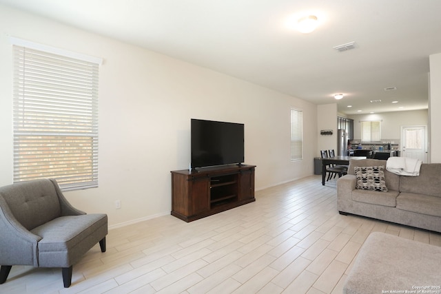 living area with baseboards, visible vents, and light wood-style flooring
