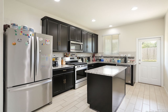 kitchen featuring a center island, recessed lighting, light stone countertops, and stainless steel appliances
