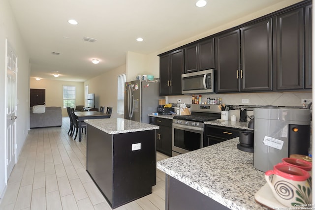 kitchen with visible vents, appliances with stainless steel finishes, a center island, light stone countertops, and recessed lighting