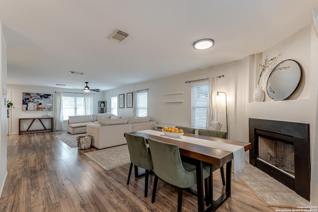 dining room with ceiling fan, visible vents, wood finished floors, and a fireplace