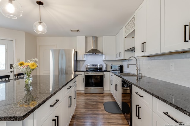 kitchen featuring dark wood-style flooring, wall chimney range hood, white cabinetry, appliances with stainless steel finishes, and backsplash