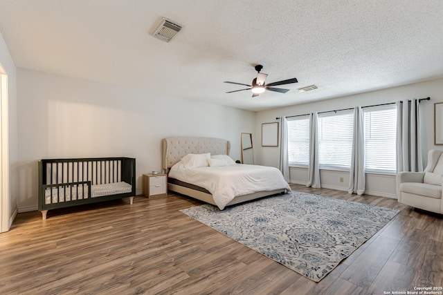 bedroom featuring visible vents, a ceiling fan, a textured ceiling, and wood finished floors