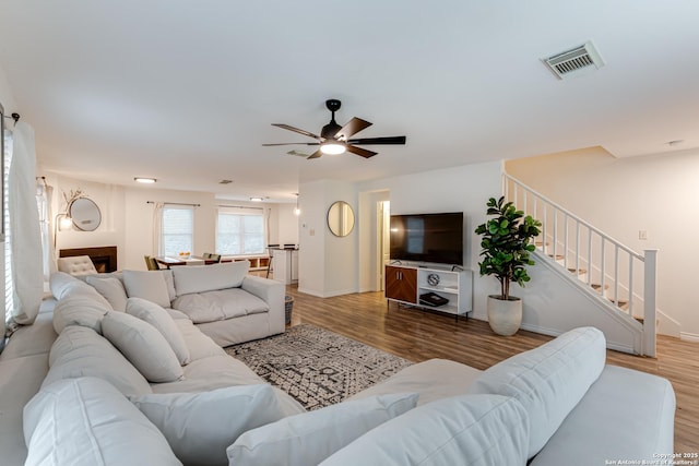 living room featuring visible vents, ceiling fan, wood finished floors, and stairway