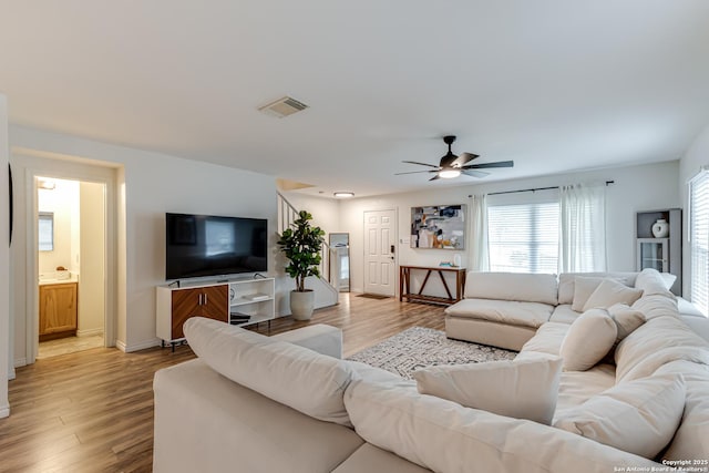 living room featuring light wood-style floors, baseboards, a ceiling fan, and visible vents