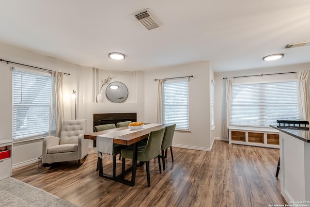 dining area featuring baseboards, visible vents, wood finished floors, and a fireplace