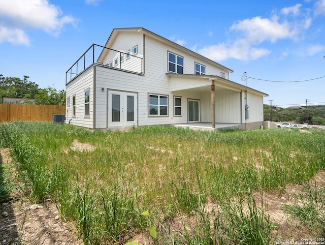 rear view of property with french doors, central AC, fence, a balcony, and a patio