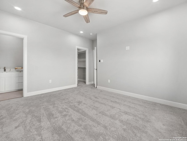 unfurnished bedroom featuring light colored carpet, recessed lighting, baseboards, and a spacious closet