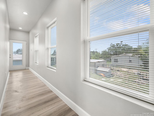 corridor featuring baseboards, recessed lighting, and wood finished floors