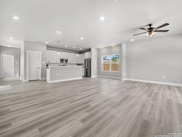unfurnished living room with baseboards, light wood-type flooring, a ceiling fan, and recessed lighting