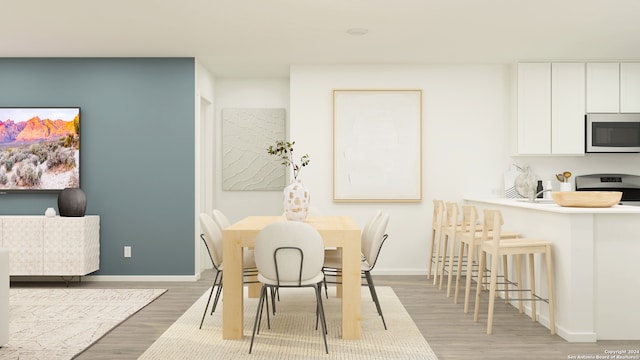 dining space featuring baseboards and light wood finished floors