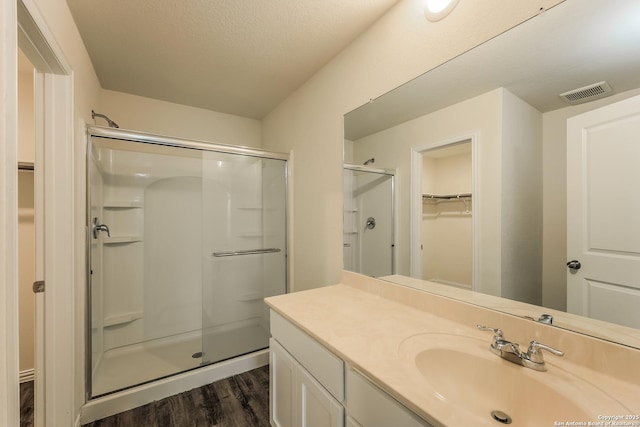 2430 Bermuda, San Antonio, TX 78222 - full bath with vanity, wood finished floors, a spacious closet, visible vents, and a stall shower