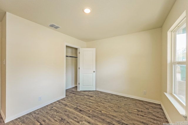 2430 Bermuda, San Antonio, TX 78222 - unfurnished bedroom featuring a closet, baseboards, multiple windows, and dark wood-type flooring