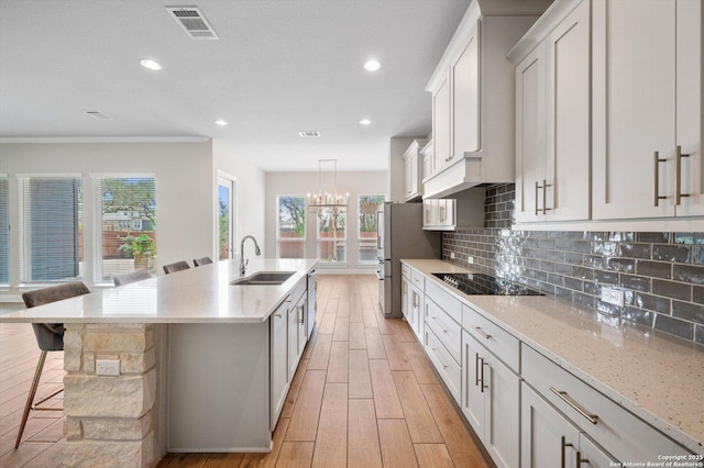 kitchen featuring visible vents, decorative backsplash, a sink, light wood-style flooring, and stainless steel appliances